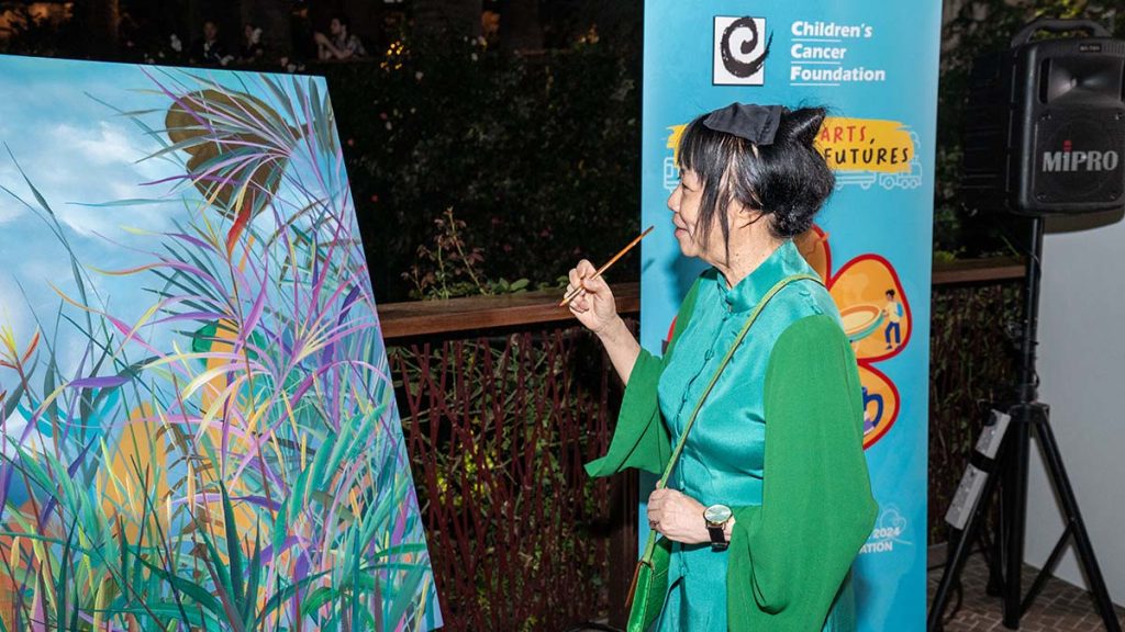 Guest of Honour Ms Jane Ittogi putting the finishing touch on a curated artwork at the Opening for the Hope Train art exhibition at Gardens by the Bay.